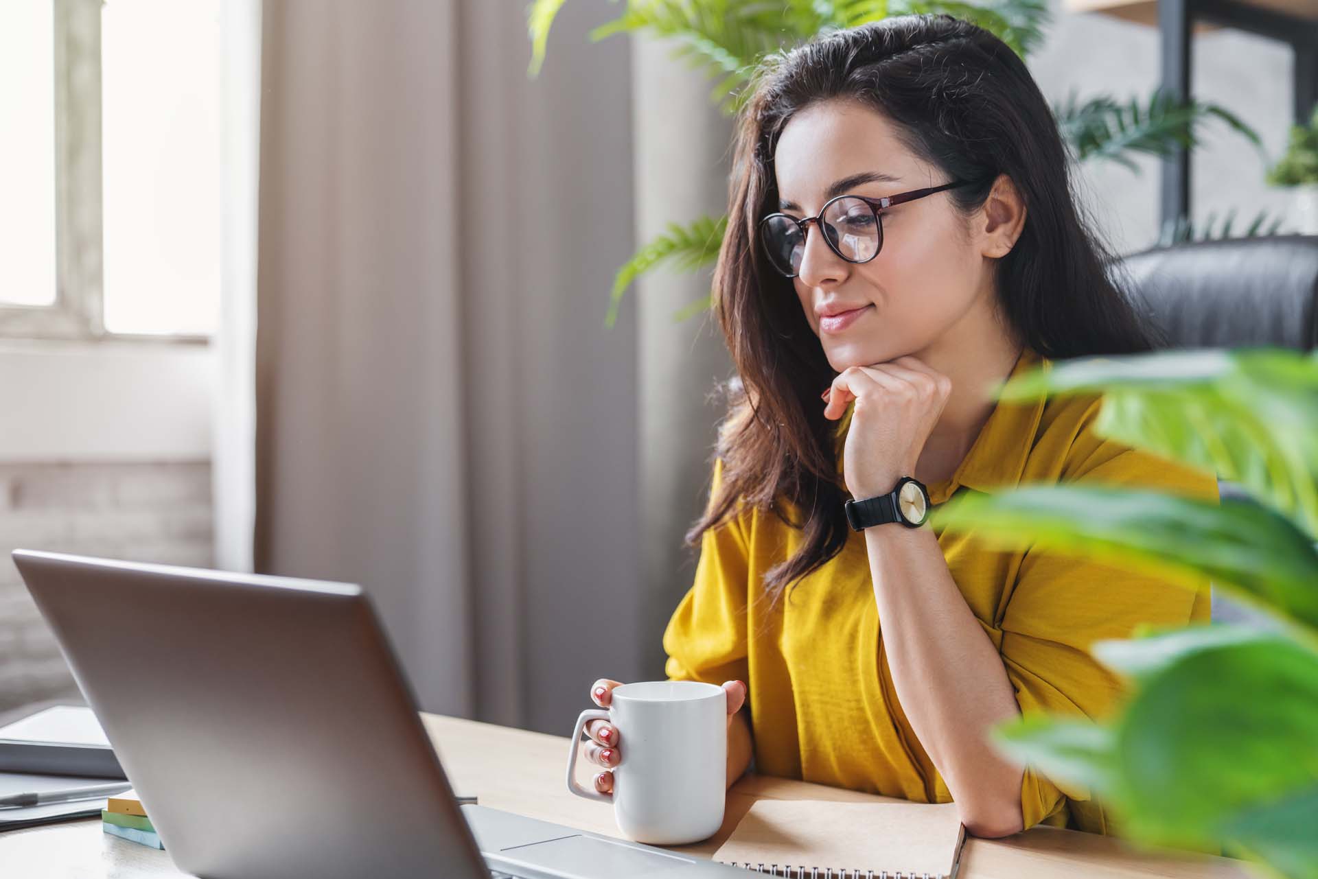Young woman enjoying her coffee while working or studying on laptop computer at home office property manager on computer
